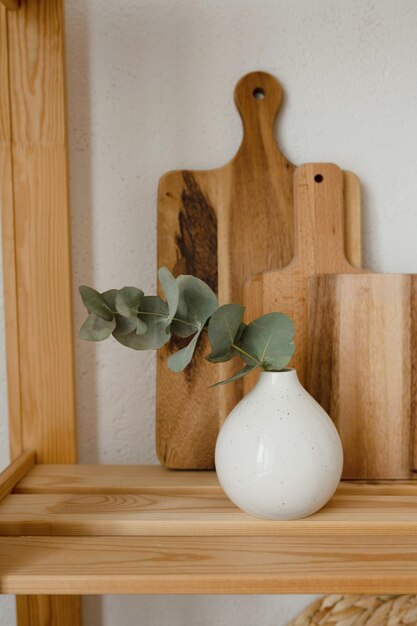 Foto vaso bianco con ramo di eucalipto su ripiano in legno