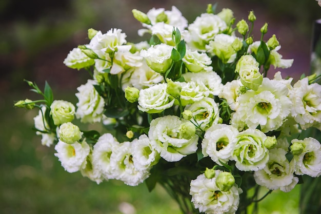 レストランで花が付いている白い花瓶はテーブルを提供しました花が付いているバスケット木花結婚式のフローリストリー