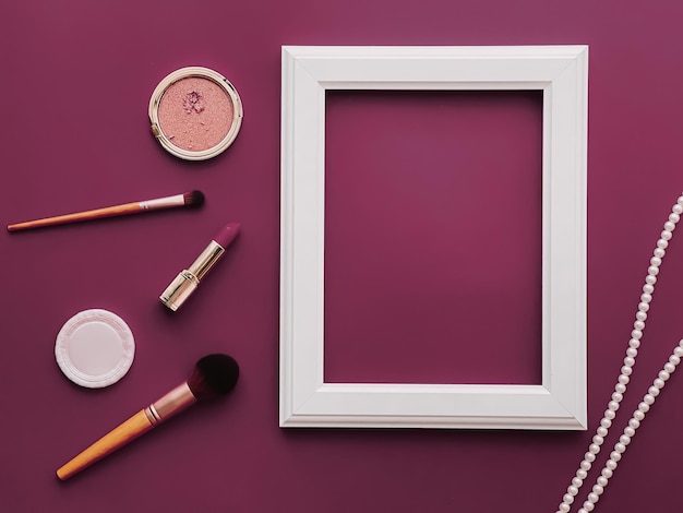 Photo white vertical art frame makeup products and pearl jewellery on purple background as flatlay design artwork print or photo album concept