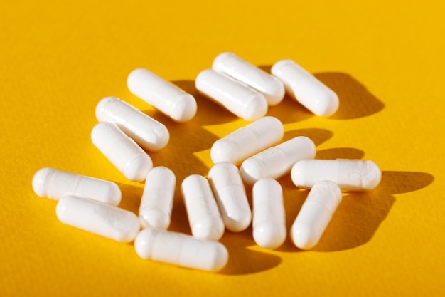 White vitamin D pills on yellow background