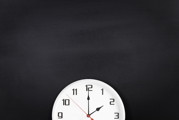 Белые настенные часы на черной доске фоновое пространство для ваших меловых надписей