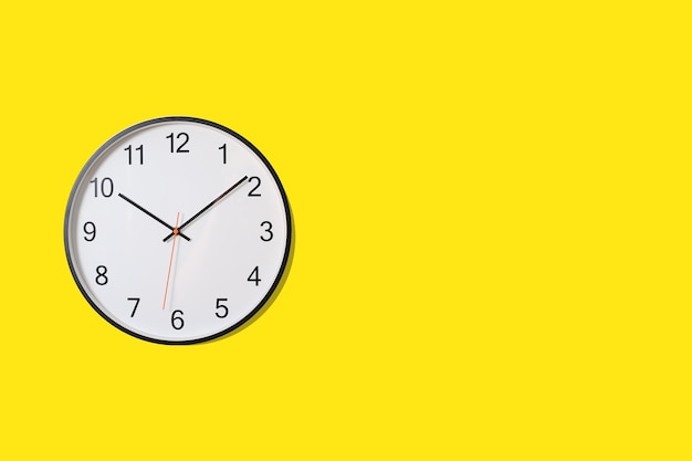 White wall clock on yellow background