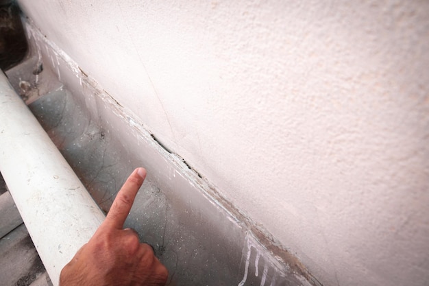 A white wall with a black base and a white wall that has a crack in it.