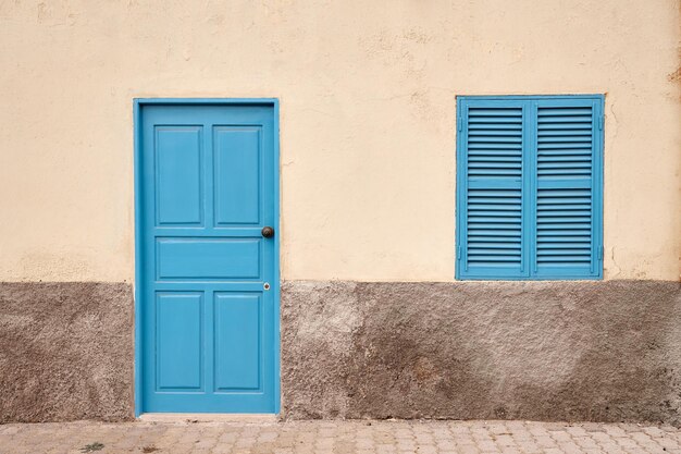 A white wall with a blue door and window