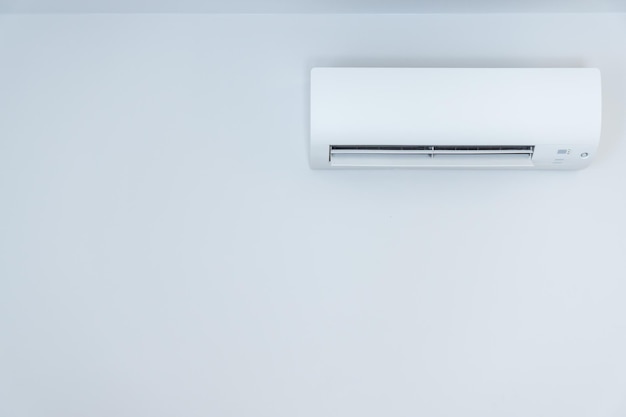 White wall with hanging air conditioning unit and copy space