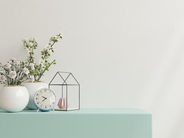 White wall with ornamental plants and decoration item on cabinet