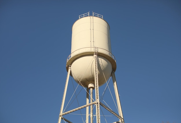 A white water tower with a blue sky in the background.