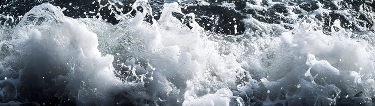 Photo 白い水の波が暗い海の表面にぶつかる