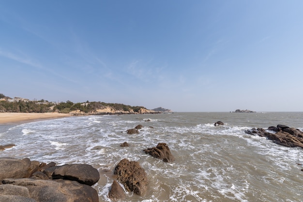 Le onde bianche battono contro le rocce nere