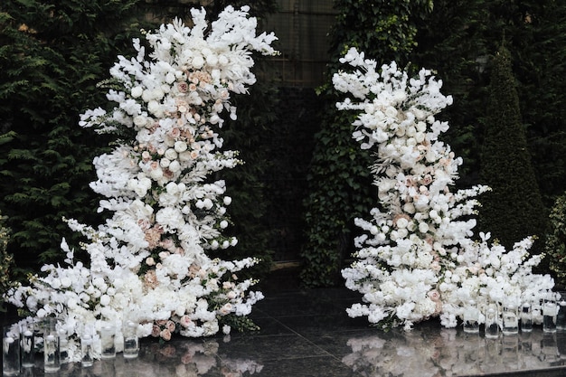 A white wedding arch with white flowers and candles