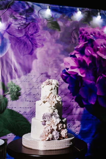 White wedding cake with pink flowers on a festive table with pastry. close up of cake. Sweet table.