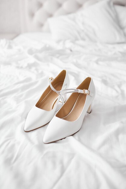 White wedding shoes are lying on the bed