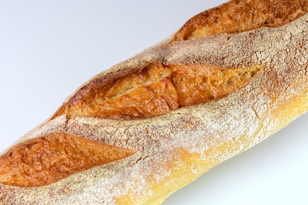 White wheat bread in the form of a baguette, on a white background close-up, healthy food