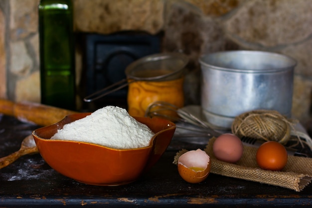 Farina di frumento bianco in ceramica uovo rotto con il tuorlo di uova intere e utensili da cucina