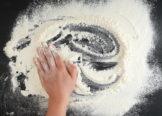 white wheat flour scattered on a black background product is spread over the surface kitchen