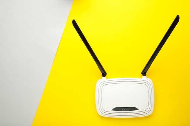 White wi-fi router with black antennas on yellow grey surface with copy space