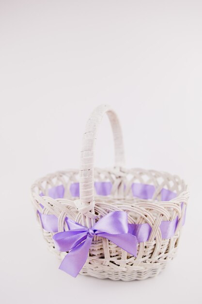 A white wicker basket with purple ribbon