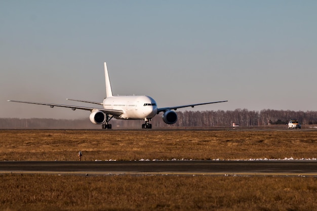 White wide body passenger airplane moves behind the Follow-me-Car on the main taxiway