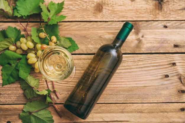 Photo white wine glass and bottle and fresh grapes on wooden background copy space