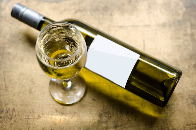 White wine in glass and bottle on golden rustic table