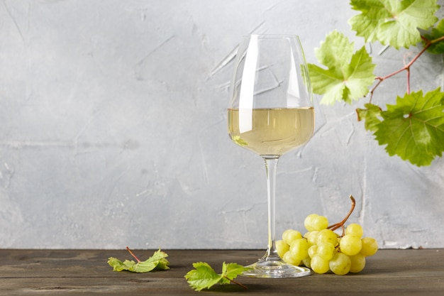 Белое вино в бокале и гроздь винограда