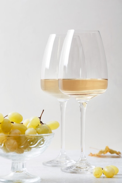 Foto vino bianco in un bicchiere e uva sul tavolo.