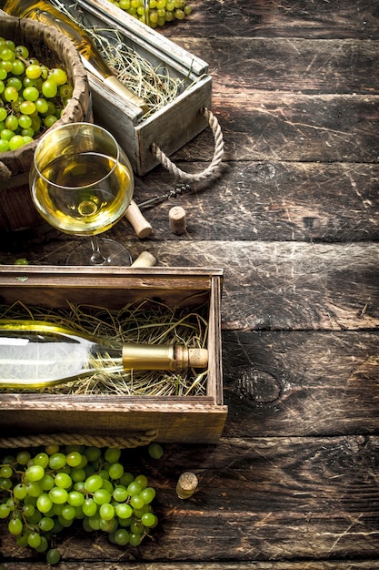 緑のブドウと古い箱に入った白ワイン。木製のテーブルの上。