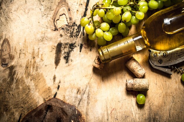 Vino bianco con grappolo d'uva. sullo sfondo di legno.