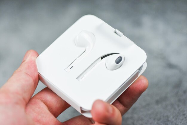White wireless bluetooth earphones or headphones smartphone Earphones in plastic storage case isolated in hand