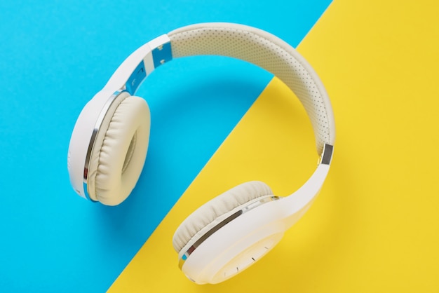 White wireless headphones on a blue and yellow background