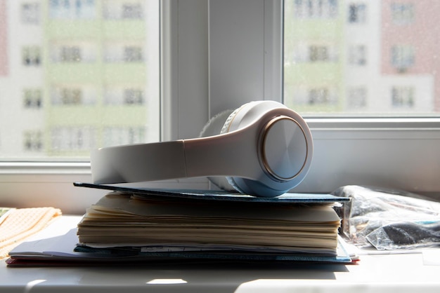 White wireless headphones lie on the diary on the windowsill