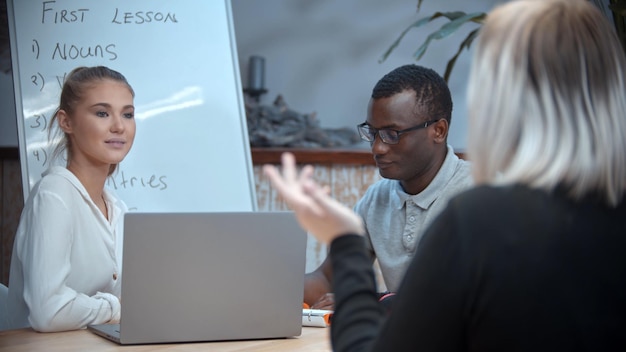 A white woman and black man having an english lesson in white class