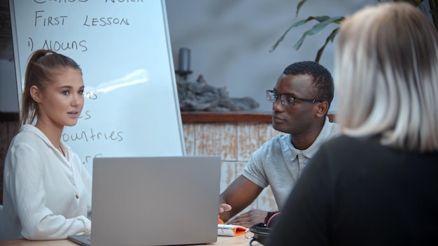 A white woman and black man having an english lesson with a teacher