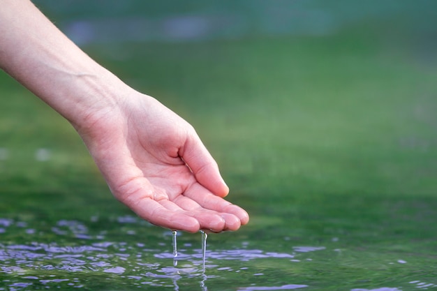 白人女性の手が水に触れます。