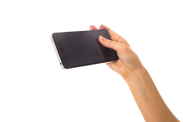 White woman's hand holding a smartphone with black screen and touching it on white background in studio