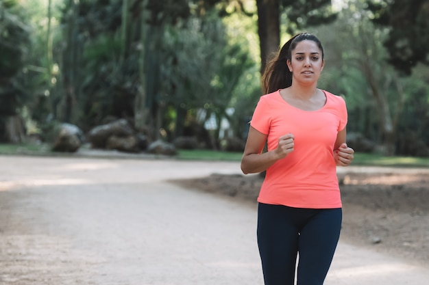 White woman smiling running through the park