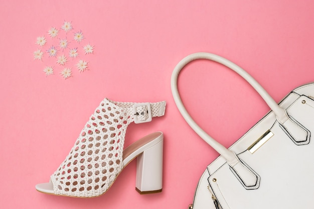 White women's shoes, white bag and pattern of color on pink surface