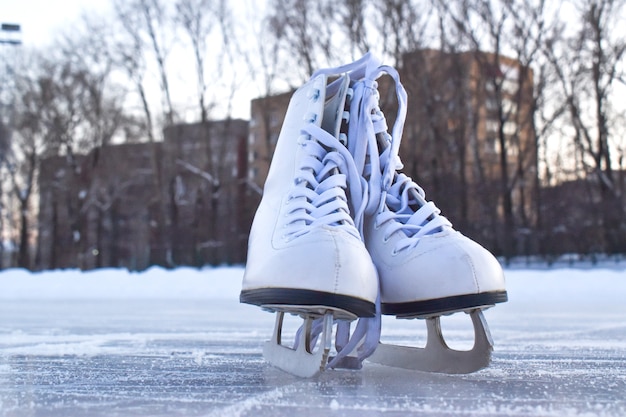 White women's skates stand on the ice. Winter entertainment ice rink.