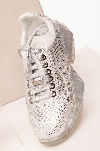 White women's sneakers are covered with shiny rhinestones on a white isolated background in the studio.