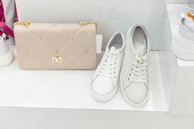Белые женские кроссовки и элегантная сумка в витрине Fashion Style Closeup