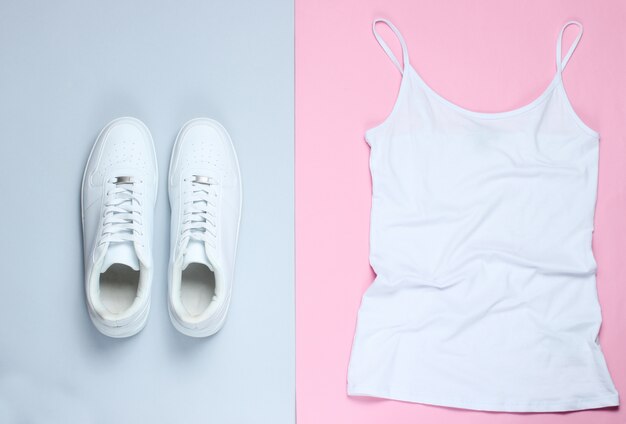 White women's t-shirt, white hipster sneakers on a pink-gray pastel background.