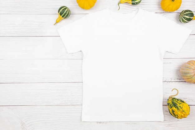 Photo white womens cotton tshirt mockup with pumpkins on white wooden background design t shirt template print presentation mock up top view flat lay