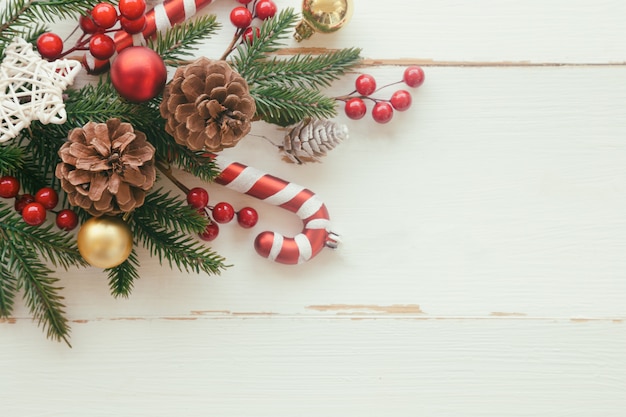 White wood with pine leaf, pine cones or conifer cone, holly balls, star, candy cane and bauble in Christmas concept. Wood plank background in top view flat lay with copy space for Christmas wallpaper