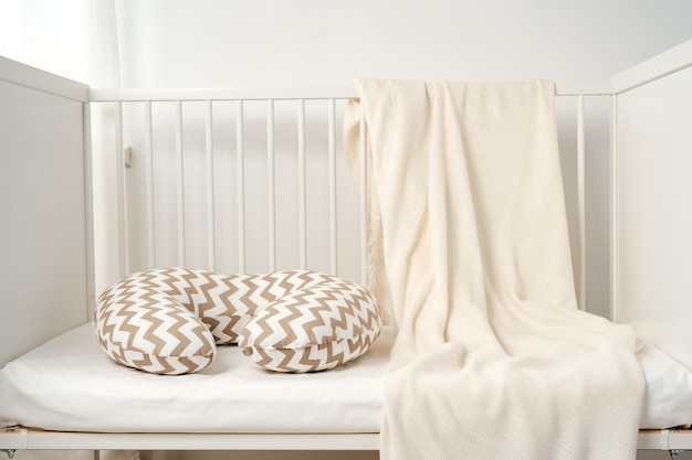 White wooden baby crib with pillow in nursery room