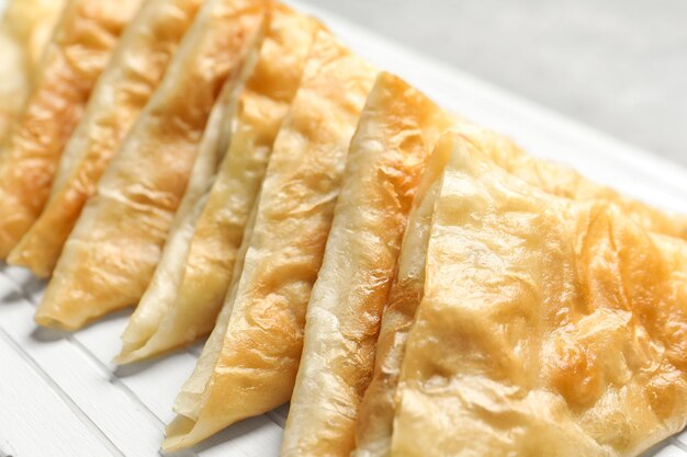 White wooden board with delicious samosas, closeup