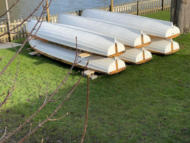 White wooden boats stored on the grass beside the river