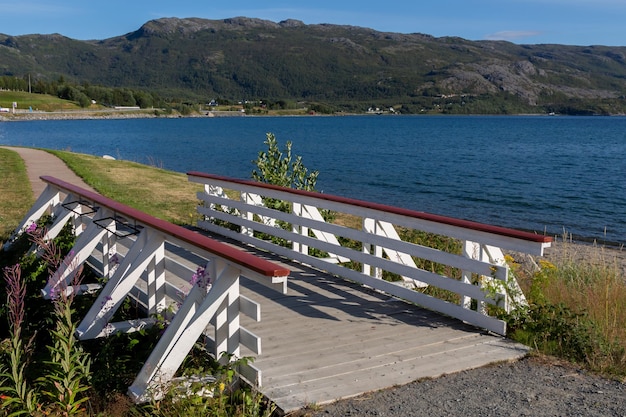 Photo white wooden bridge on lake shore with mountains on the horizon