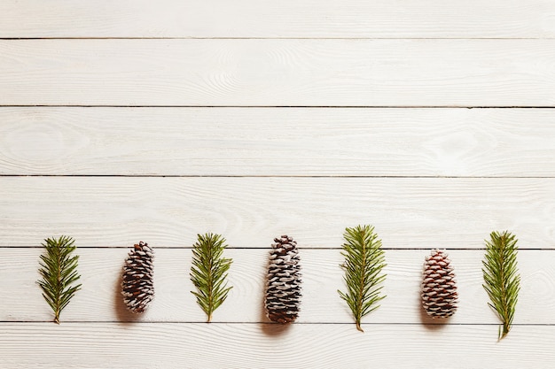 Photo white wooden christmas background with fir branches and cones, top view, copyspace.