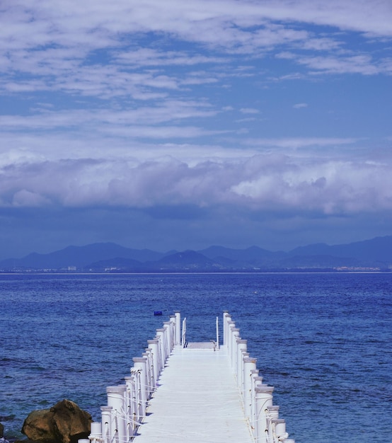 A white wooden dock with a mountain in the background.