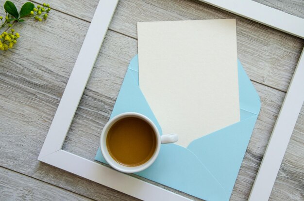 White wooden frame and blue envelope white postcard copyspace small yellow flowers and green leaves